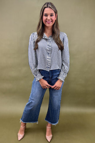 Woman wearing a striped shirt and jeans against a green background