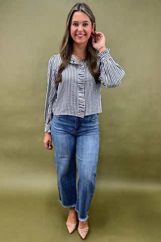 Woman wearing a striped shirt and jeans against a green background