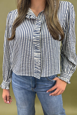 Person wearing a black and white striped shirt with blue jeans on a beige background