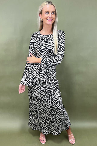 Woman wearing a zebra print dress against a green background