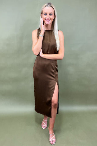 Woman wearing a brown dress with a slit on a green background