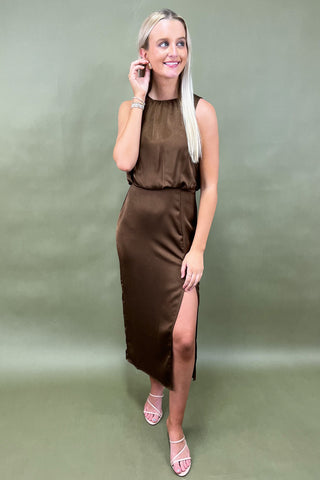Woman wearing a brown dress with a slit on a green background