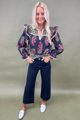 Woman wearing a floral blouse and jeans on a plain background