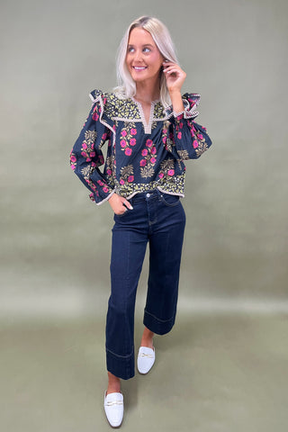Woman wearing a floral blouse and jeans on a plain background