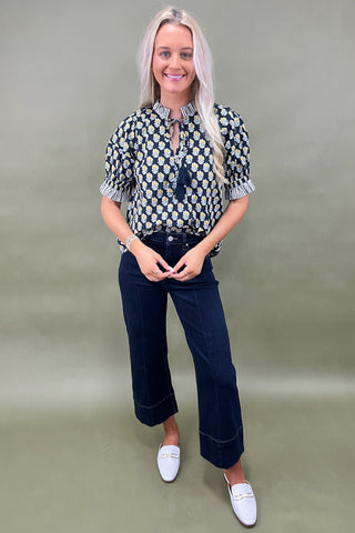 Floral print blouse with tassel tie neckline and striped trim sleeves styled with wide leg dark denim jeans.