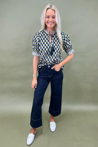 Floral print blouse with tassel tie neckline and striped trim sleeves styled with wide leg dark denim jeans.