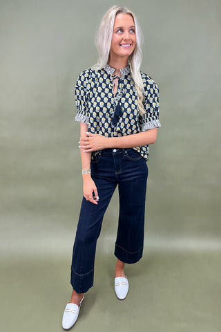 Floral print blouse with tassel tie neckline and striped trim sleeves styled with wide leg dark denim jeans.