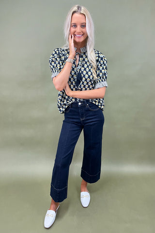 Floral print blouse with tassel tie neckline and striped trim sleeves styled with wide leg dark denim jeans.