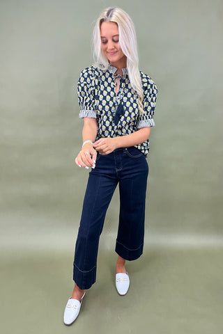 Floral print blouse with tassel tie neckline and striped trim sleeves styled with wide leg dark denim jeans.