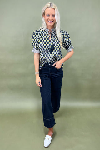 Floral print blouse with tassel tie neckline and striped trim sleeves styled with wide leg dark denim jeans.
