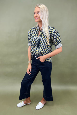 Floral print blouse with tassel tie neckline and striped trim sleeves styled with wide leg dark denim jeans.