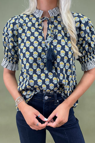 Floral print blouse with tassel tie neckline and striped trim sleeves styled with wide leg dark denim jeans.