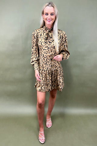 Woman wearing a leopard print dress against a plain background