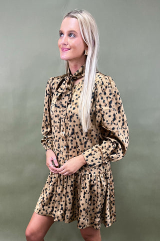 Woman wearing a leopard print dress against a plain background