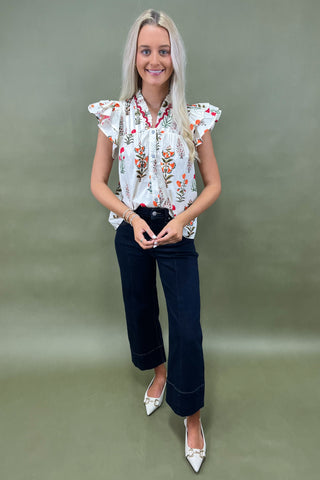 White floral ruffle sleeve blouse with button front styled with dark wide leg cropped jeans and white pointed loafers