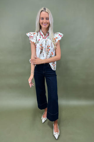 White floral ruffle sleeve blouse with button front styled with dark wide leg cropped jeans and white pointed loafers