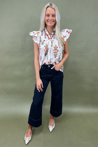 White floral ruffle sleeve blouse with button front styled with dark wide leg cropped jeans and white pointed loafers