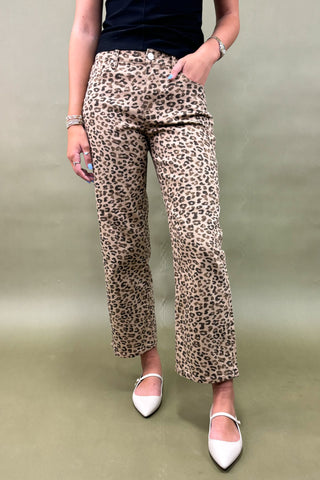 Person wearing leopard print pants on a plain background
