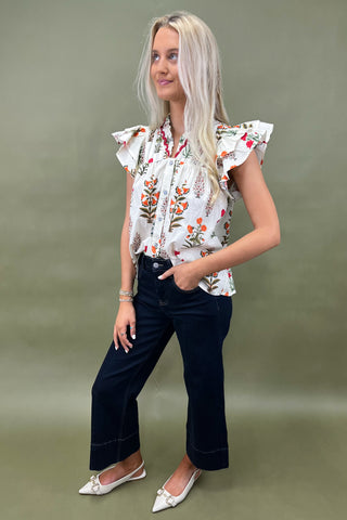 White floral ruffle sleeve blouse with button front styled with dark wide leg cropped jeans and white pointed loafers