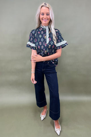 Black floral ruffle sleeve blouse with striped trim details styled with dark wide leg cropped jeans and white pointed loafers