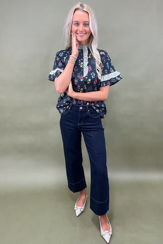 Black floral ruffle sleeve blouse with striped trim details styled with dark wide leg cropped jeans and white pointed loafers