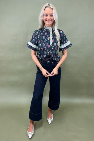 Black floral ruffle sleeve blouse with striped trim details styled with dark wide leg cropped jeans and white pointed loafers
