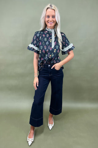 Black floral ruffle sleeve blouse with striped trim details styled with dark wide leg cropped jeans and white pointed loafers