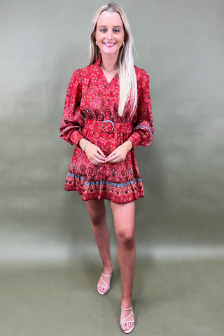 Woman wearing a red patterned dress against a plain background