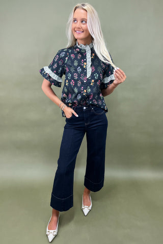 Black floral ruffle sleeve blouse with striped trim details styled with dark wide leg cropped jeans and white pointed loafers
