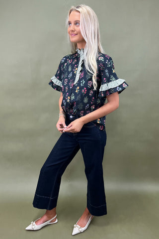 Black floral ruffle sleeve blouse with striped trim details styled with dark wide leg cropped jeans and white pointed loafers