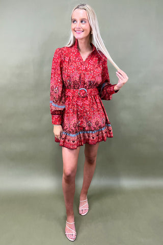 Woman wearing a red patterned dress against a plain background