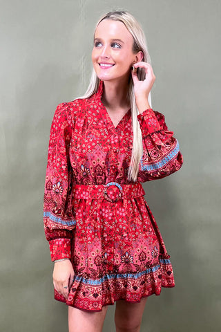 Woman wearing a red patterned dress against a green background