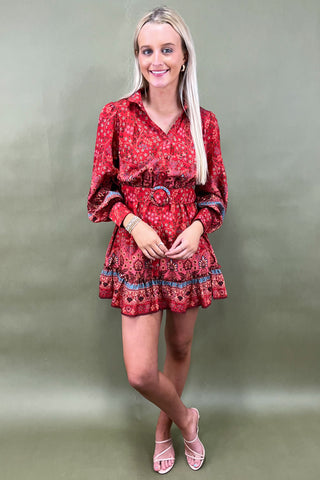 Woman wearing a red patterned dress against a plain background