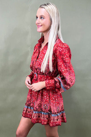 Woman wearing a red patterned dress against a plain background