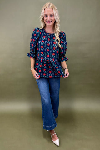 Woman wearing a floral blouse and jeans against a green background