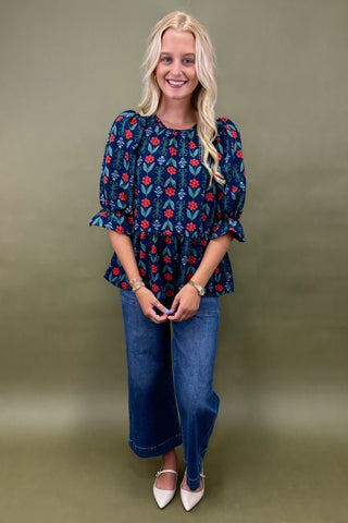 Woman wearing a blue floral blouse and jeans against a green background