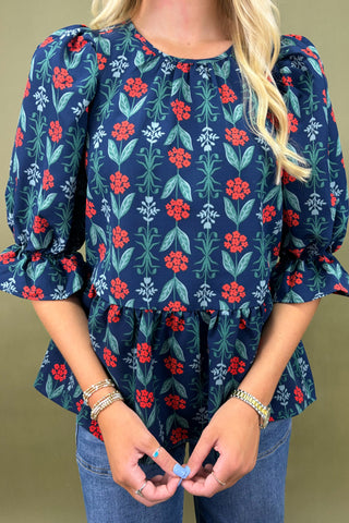 Woman wearing a blue floral blouse and jeans against a green background