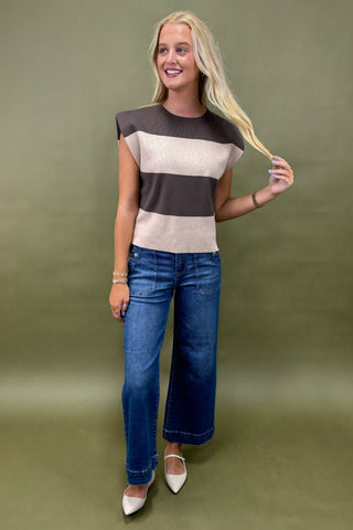 Woman wearing a striped shirt and blue jeans against a green background