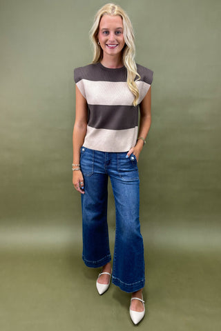 Woman wearing a striped shirt and blue jeans against a green background