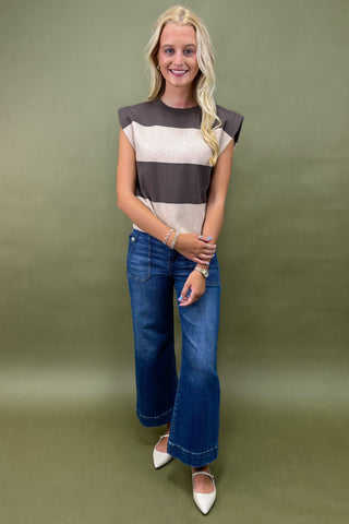 Woman wearing a striped shirt and jeans against a green background