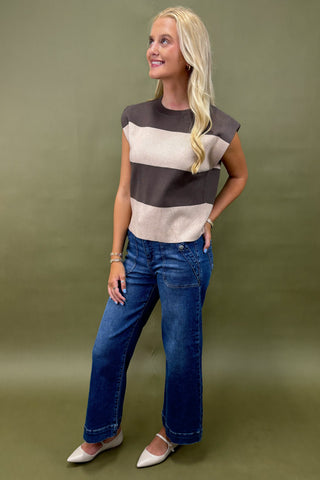 Woman wearing a striped shirt and blue jeans against a green background