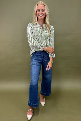 Woman wearing a striped shirt sage jean against a plain background