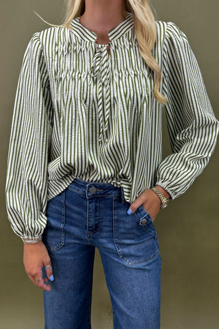 Woman wearing a striped blouse and blue jeans against a plain background