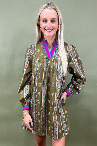 Woman wearing a green patterned dress with long sleeves against a green background