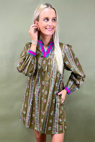 Woman wearing a patterned dress with long sleeves on a green background