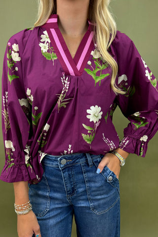 Purple floral blouse worn by a person with a green background