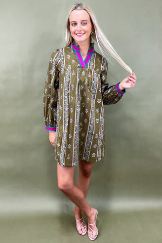 Woman wearing a patterned dress against a plain background