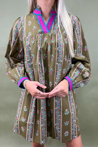 Person wearing a patterned dress with long sleeves on a plain background