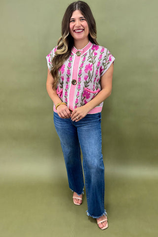 Woman wearing a floral top and blue jeans on a green background
