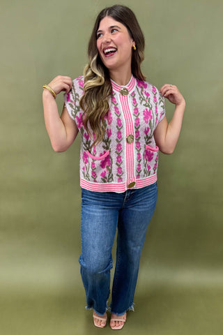Woman wearing a floral blouse and jeans against a green background